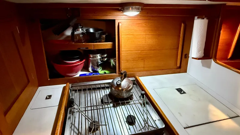 Slide: The Image of 1989 J Boats J/40 yacht galley with stove, kettle, and wooden cabinetry. - 24