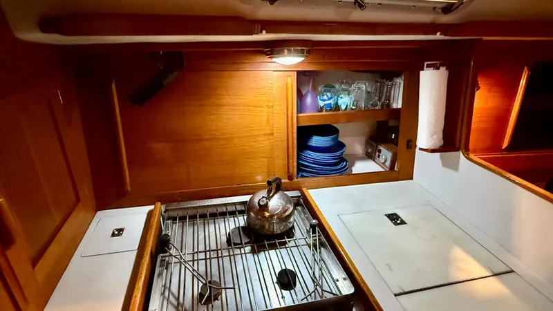 Slide: The Image of 1989 J Boats J/40 yacht kitchen with stove, kettle, and wooden cabinetry. - 25