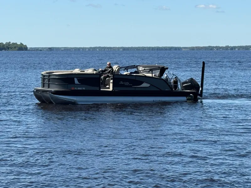Slide: The Image of 2022 Barletta Lusso 23U pontoon boat cruising on a calm lake. - 0