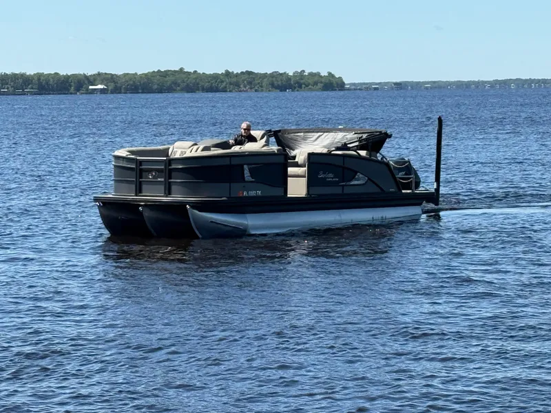 Slide: The Image of 2022 Barletta Lusso 23U pontoon boat cruising on a lake under clear skies. - 1