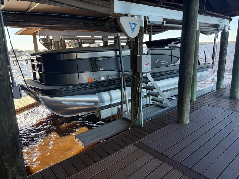 Slide: The Image of 2022 Barletta Lusso 23U pontoon boat docked on a lift by the water. - 10