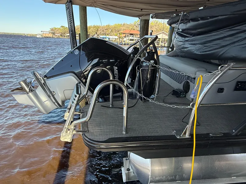 Slide: The Image of 2022 Barletta Lusso 23U pontoon boat with Mercury outboard motor docked by the water. - 11