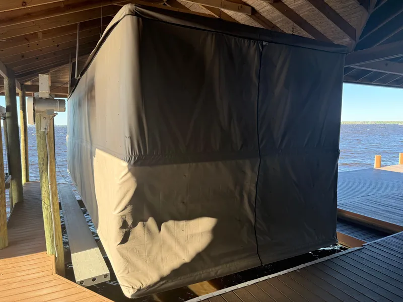 Slide: The Image of Covered 2022 Barletta Lusso 23U boat on a dock lift, under a wooden roof. - 13