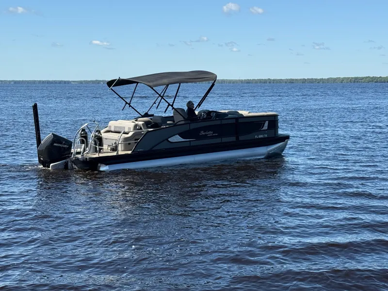 Slide: The Image of 2022 Barletta Lusso 23U pontoon boat on a calm lake under a clear blue sky. - 4