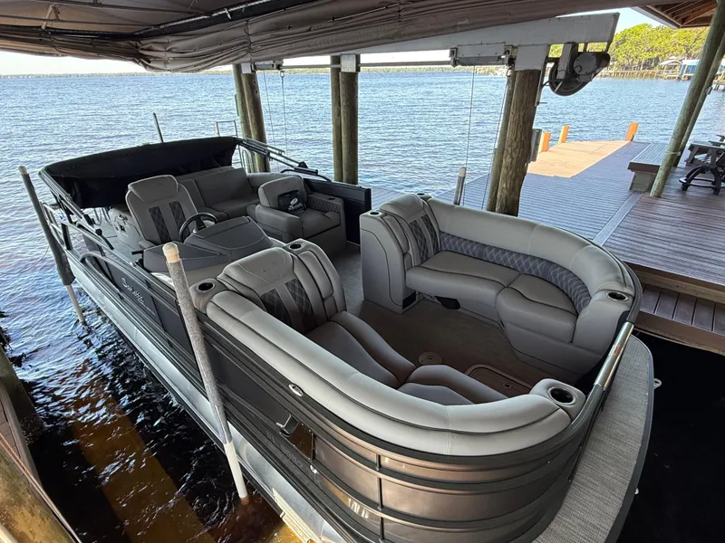 Slide: The Image of 2022 Barletta Lusso 23U pontoon boat docked by a serene lakeside. - 6