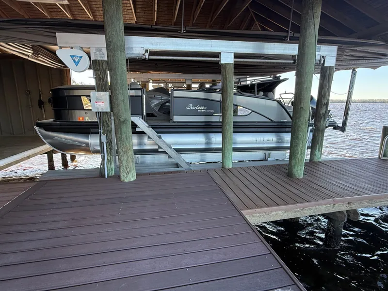 Slide: The Image of 2022 Barletta Lusso 23U pontoon boat docked under a wooden shelter. - 9