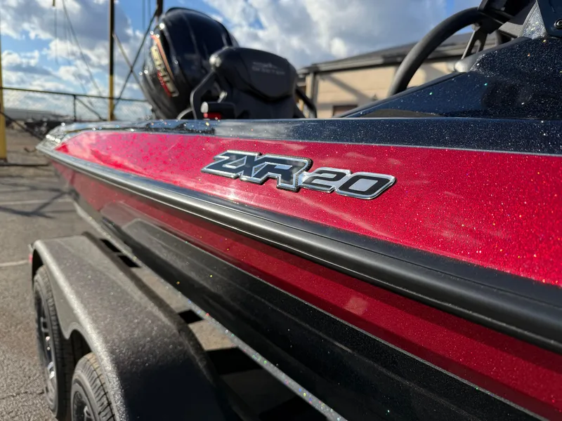 Slide: The Image of 2025 Skeeter ZXR20 boat, red and black, parked outdoors under a blue sky. - 14
