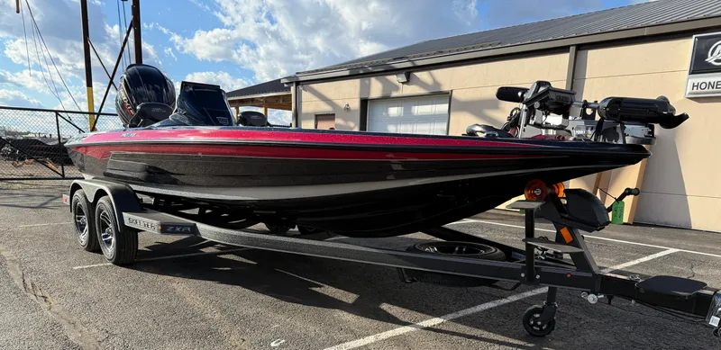 Slide: The Image of 2025 Skeeter ZXR20 boat on trailer, parked outdoors, under a partly cloudy sky. - 3