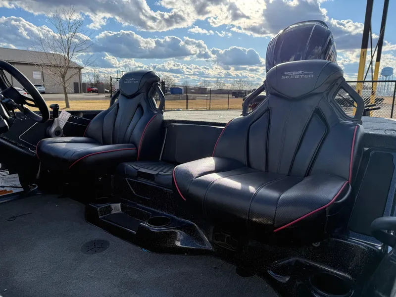 Slide: The Image of 2025 Skeeter ZXR20 boat interior with black leather seats and red accents under a cloudy sky. - 9
