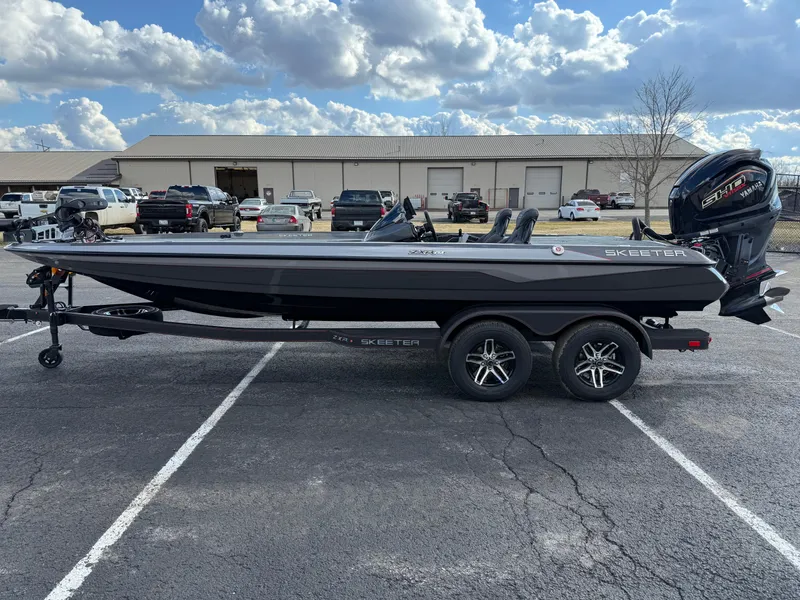 Slide: The Image of 2025 Skeeter ZXR21 boat on trailer in parking lot, under cloudy sky. - 1