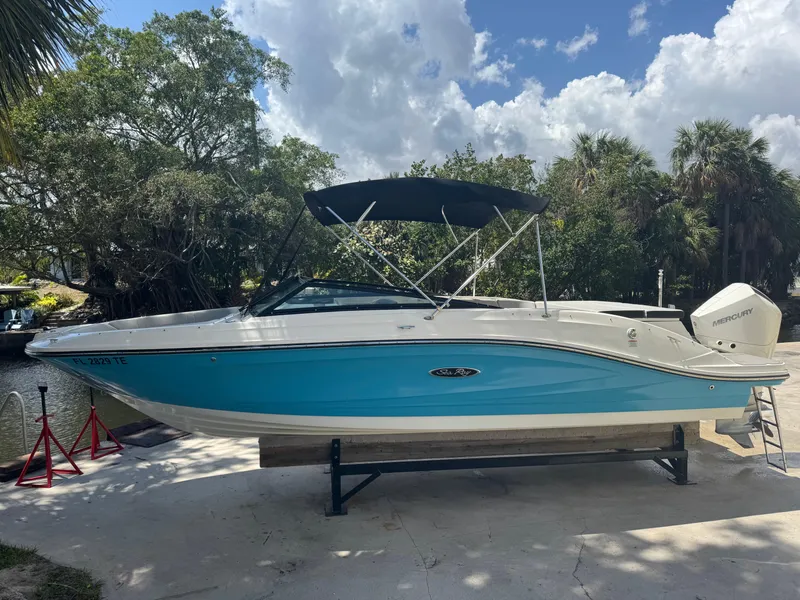 The Image of 2022 Sea Ray SPX 230 OB boat with blue hull, docked outdoors under a cloudy sky. - 0