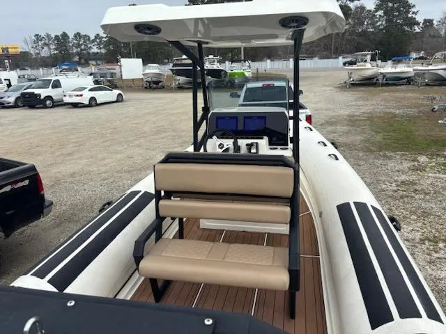 Slide: The Image of 2022 Brig Navigator 24 boat with beige seating and dual screens, parked in a lot. - 13
