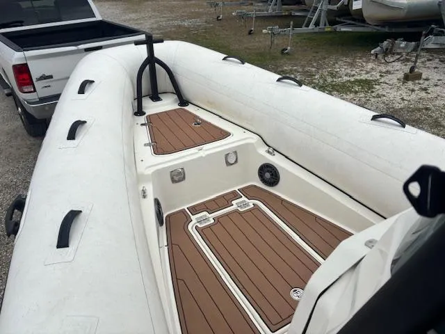 Slide: The Image of 2022 Brig Navigator 24 inflatable boat with wood-style deck, parked near a truck. - 17