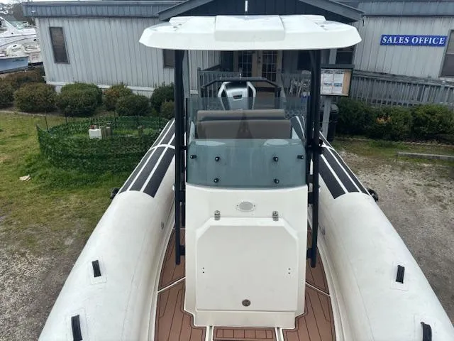 Slide: The Image of 2022 Brig Navigator 24 boat with white deck and black accents, docked near sales office. - 18