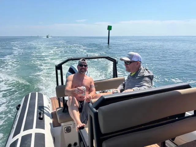 Slide: The Image of Two people relaxing on a 2022 Brig Navigator 24 boat in open water. - 25