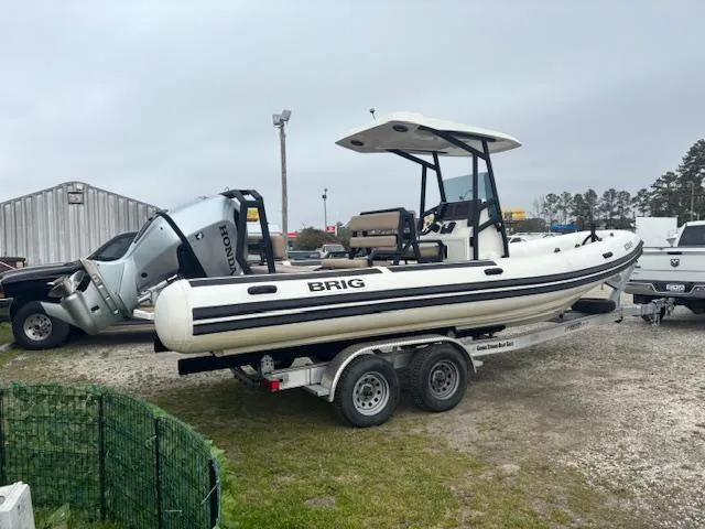 Slide: The Image of 2022 Brig Navigator 24 boat on trailer with Honda outboard motor, parked outdoors. - 9