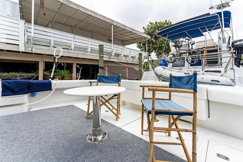 Slide: The Image of 2003 Bertram 570 Moppie boat deck with chairs and table, docked near a marina. - 10