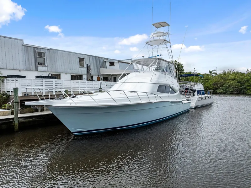 Slide: The Image of 2003 Bertram 570 Moppie yacht docked by a waterfront building. - 2