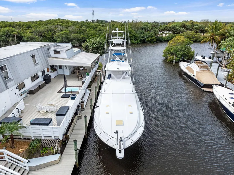 Slide: The Image of 2003 Bertram 570 Moppie yacht docked by a modern waterfront home. - 3