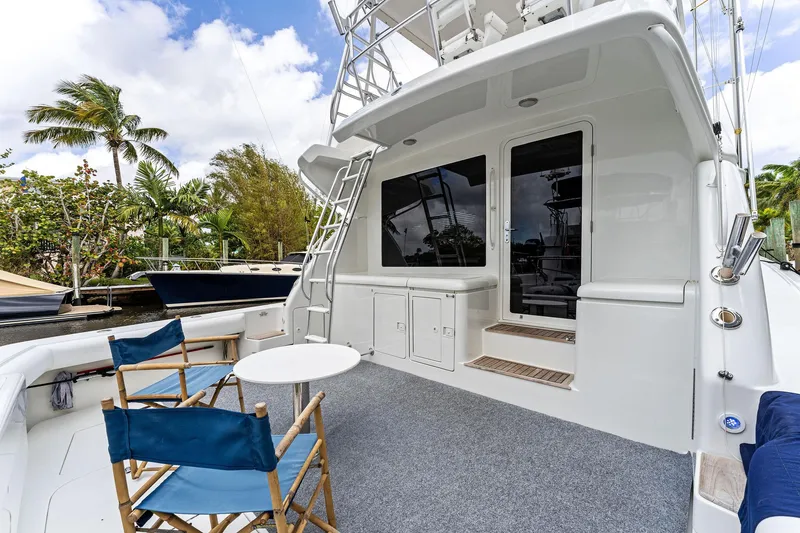 Slide: The Image of 2003 Bertram 570 Moppie yacht deck with chairs, table, and ladder under blue sky. - 6