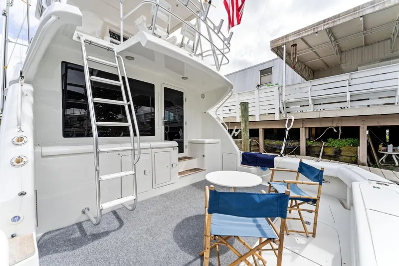 Slide: The Image of 2003 Bertram 570 Moppie yacht deck with seating and ladder, docked at marina. - 8