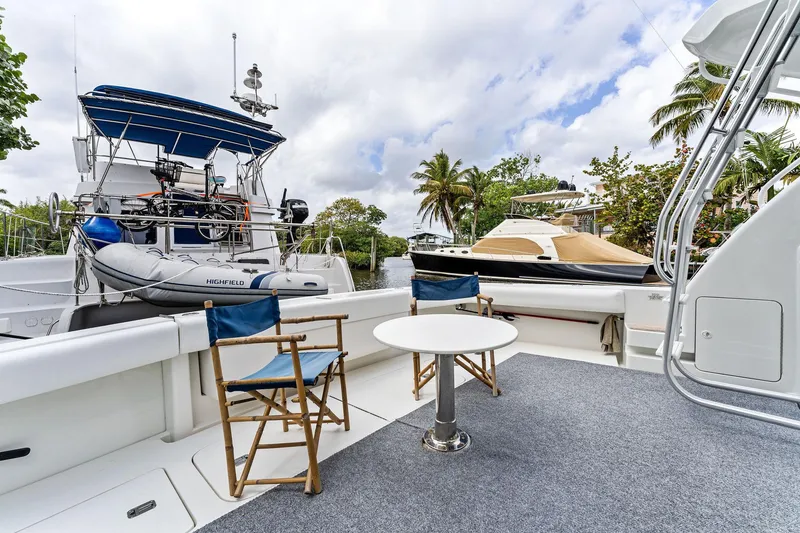 Slide: The Image of 2003 Bertram 570 Moppie yacht deck with chairs and table, docked near other boats. - 9