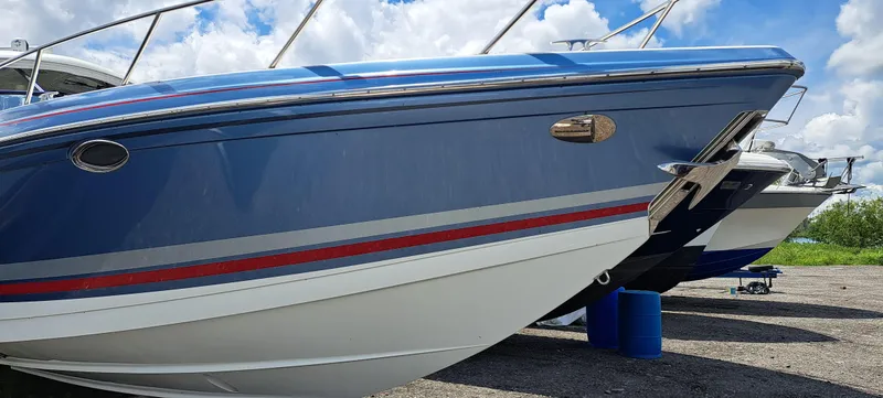 Slide: The Image of 2018 Formula 400 Super Sport boat, blue hull, parked on gravel under a cloudy sky. - 6