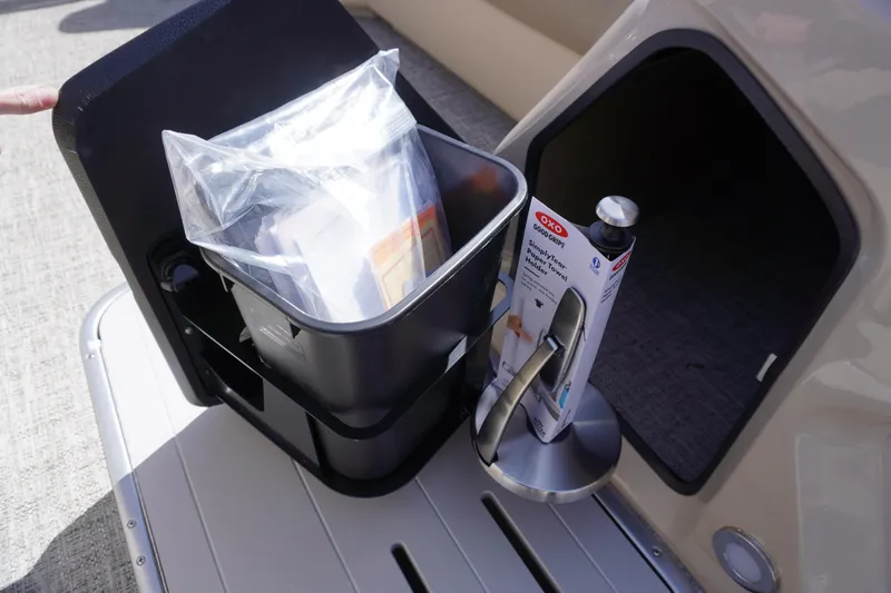 Slide: The Image of Storage compartment on 2025 Premier 250 Sunsation RS boat with accessories and cleaning supplies. - 19