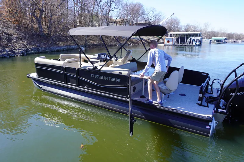 Slide: The Image of 2025 Premier 250 Sunsation RS pontoon boat on a calm lake with a canopy. - 2