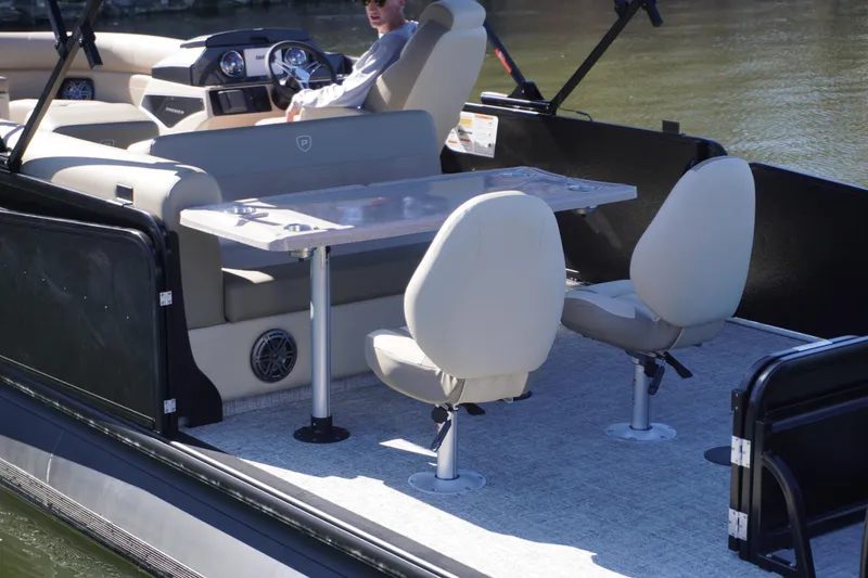 Slide: The Image of 2025 Premier 250 Sunsation RS pontoon boat interior with seating and table on the water. - 3