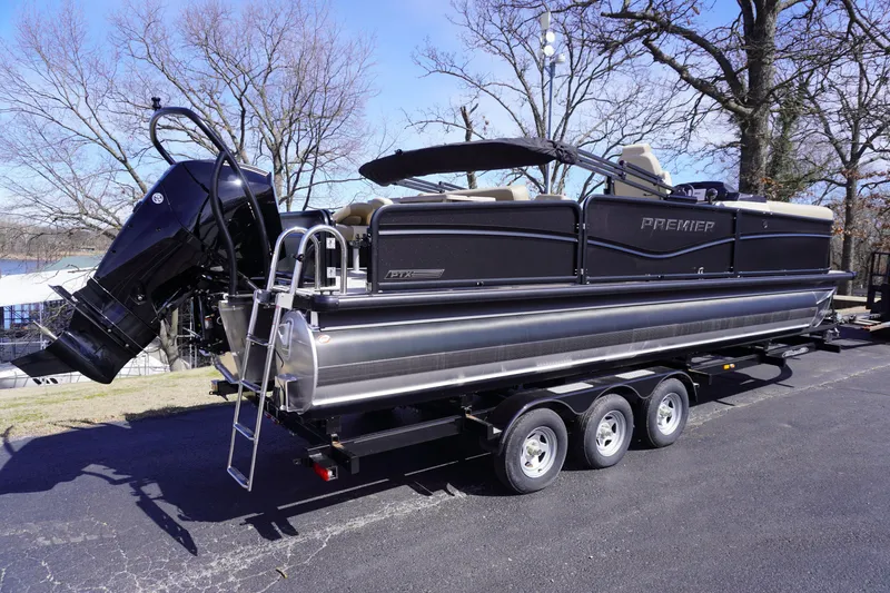 Slide: The Image of 2025 Premier 250 Sunsation RS pontoon boat on a trailer, parked outdoors. - 6