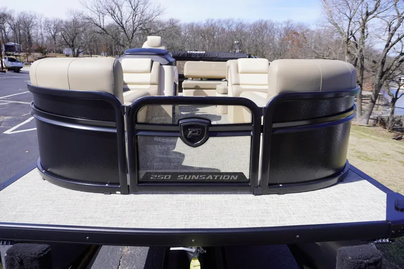 Slide: The Image of 2025 Premier 250 Sunsation RS pontoon boat with beige seating, parked outdoors. - 9