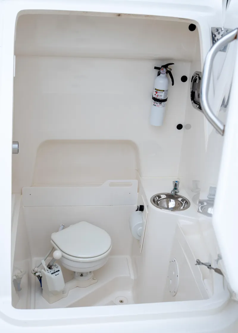 Slide: The Image of 2018 Pursuit C 260 Center Console boat interior with toilet and fire extinguisher. - 16