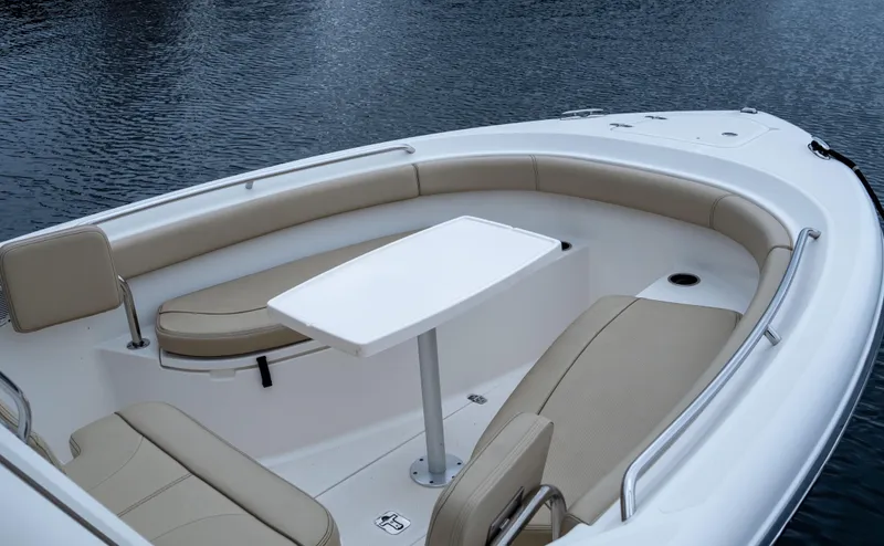 Slide: The Image of 2018 Pursuit C 260 Center Console boat with cushioned seating and table on calm water. - 18