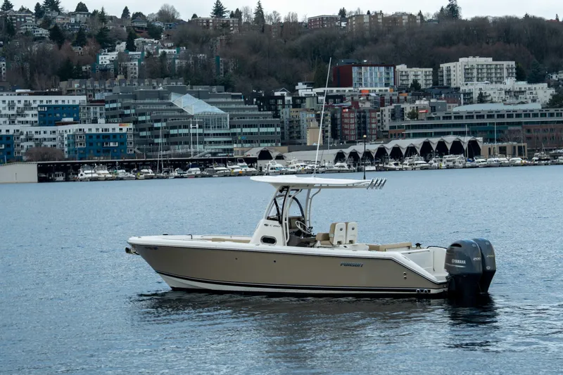 Slide: The Image of 2018 Pursuit C 260 Center Console boat on water with cityscape background. - 2