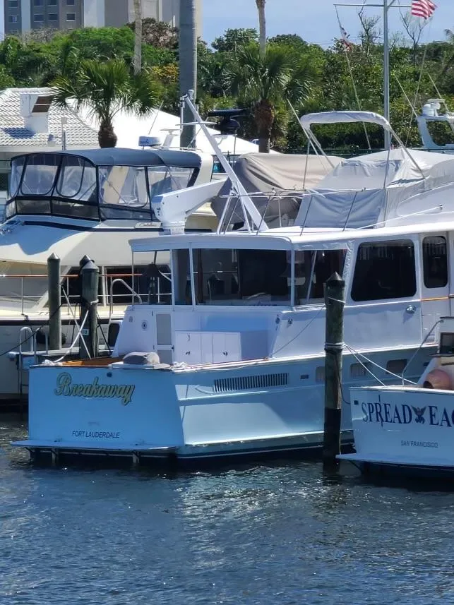 Slide: The Image of 1964 Huckins Atlantic yacht docked at a marina, surrounded by other boats. - 2