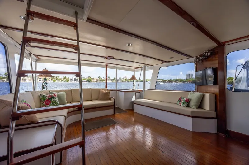 Slide: The Image of 1964 Huckins Atlantic yacht interior with wooden flooring, spacious seating, and large windows overlooking the water. - 26