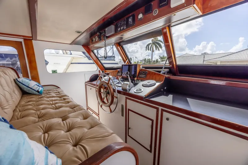 Slide: The Image of 1964 Huckins Atlantic yacht interior with plush seating and classic wooden helm. - 32