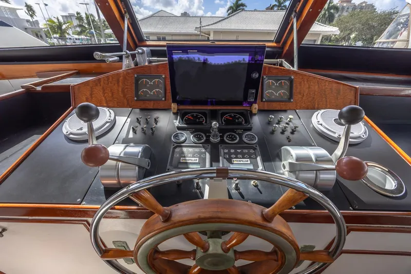 Slide: The Image of 1964 Huckins Atlantic yacht helm with wooden wheel and modern navigation controls. - 35