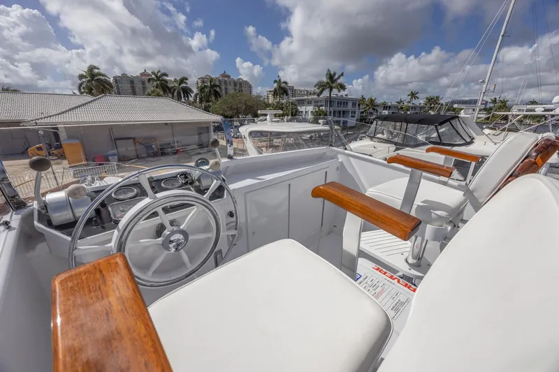 Slide: The Image of 1964 Huckins Atlantic yacht helm with wooden accents, docked under a cloudy sky. - 39