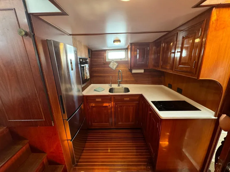 Slide: The Image of 1964 Huckins Atlantic yacht kitchen with wooden cabinetry and modern appliances. - 49