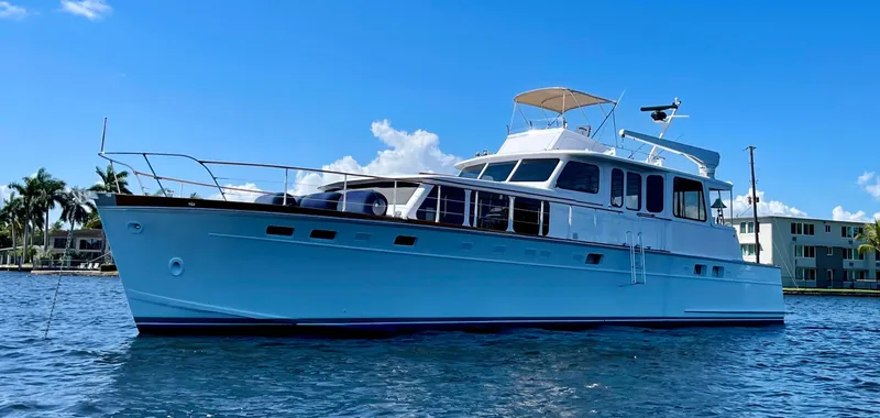 Slide: The Image of 1964 Huckins Atlantic yacht on water, clear sky, palm trees in background. - 7