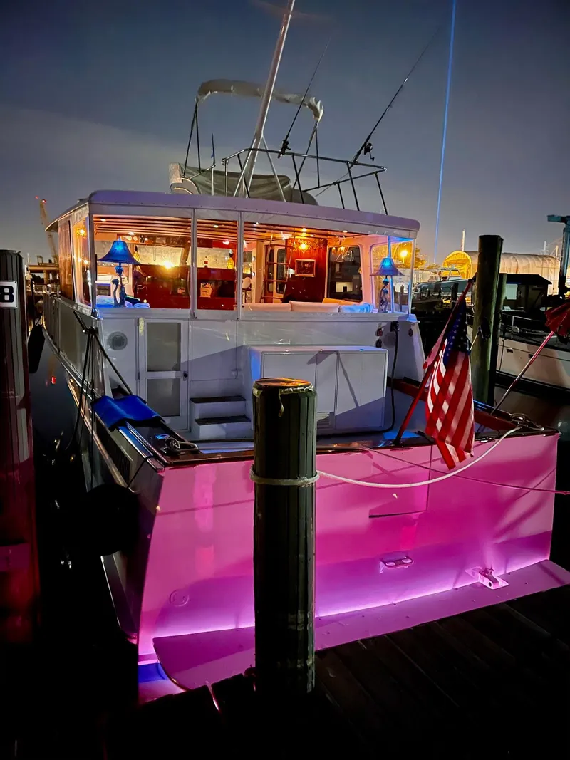 Slide: The Image of 1964 Huckins Atlantic boat docked at night with vibrant lighting and American flag. - 8