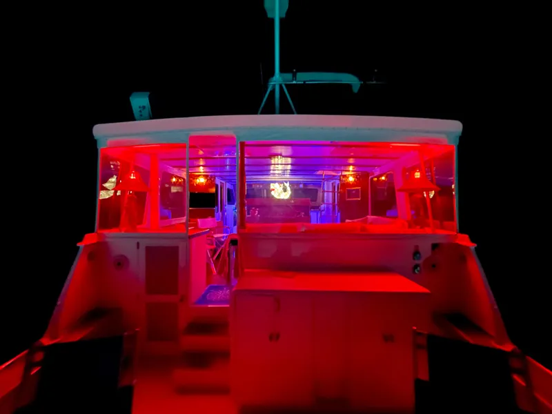 Slide: The Image of 1964 Huckins Atlantic boat with vibrant red and blue interior lighting at night. - 9