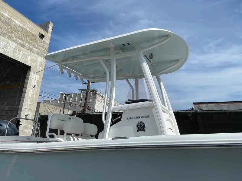 Slide: The Image of 2021 Sea Hunt Ultra 219 boat with T-top under a clear blue sky. - 14