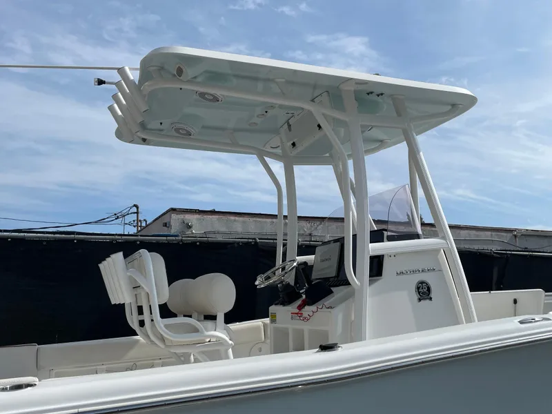 Slide: The Image of 2021 Sea Hunt Ultra 219 boat with T-top and dual seating, under a clear blue sky. - 15