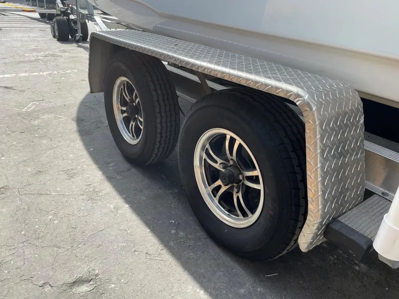 Slide: The Image of Trailer wheels of a 2021 Sea Hunt Ultra 219 boat on a sunny day. - 19