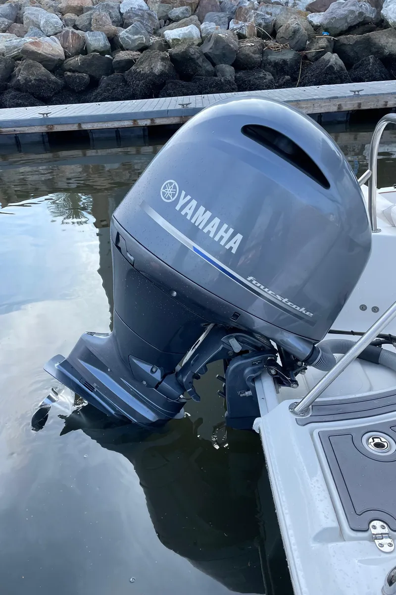 Slide: The Image of 2021 Sea Hunt Ultra 219 with Yamaha outboard motor, docked by rocky shoreline. - 45