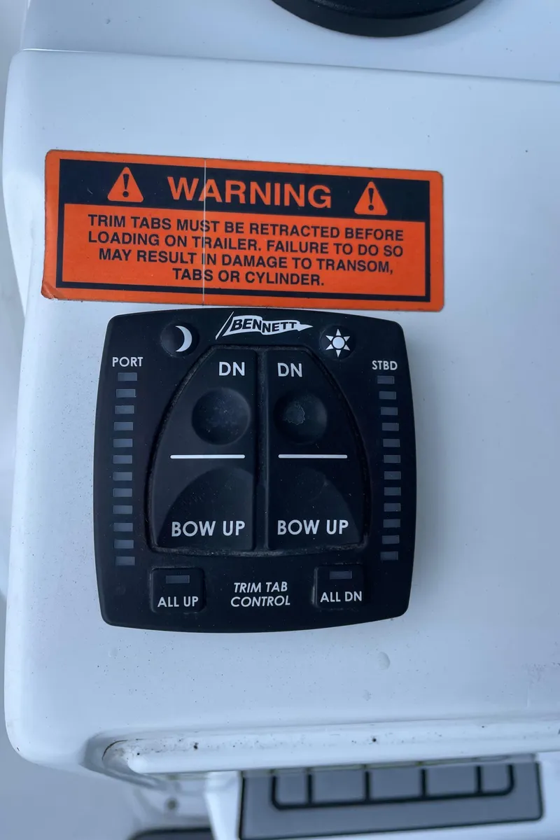 Slide: The Image of Trim tab control panel on 2021 Sea Hunt Ultra 219 boat with warning label. - 47