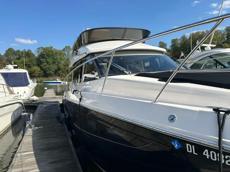 Slide: The Image of 2021 Regal 42 FXO yacht docked at marina, clear sky, lush trees in background. - 8